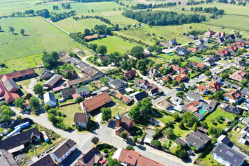 Aerial view from the edge of a village in the north of Germany with agricultural land and small patches of forest in the surrounding area