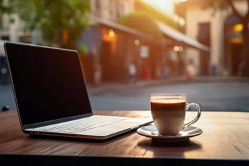 Fotobehang sunset lighting of laptop on table alongside a cup coffee in set against in background of blurred cafe and restaurant. lifestyle concept of business and rest. © cwa