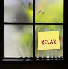 Stick note on window with handwritten text RELAX, reminder our thoughts which are scattered and...