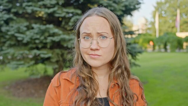 Woman smirks looking confused and flirty scrunching eyebrows to puckered kissing lips