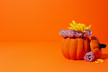 Pumpkin with flowers on orange background, space for text