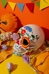 Mexican skull, maracas and zucchini in shopping cart on orange background, close up