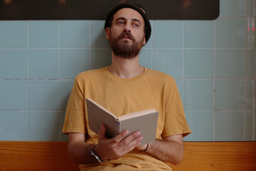 Handsome young man in a yellow T-shirt with a book in his hands