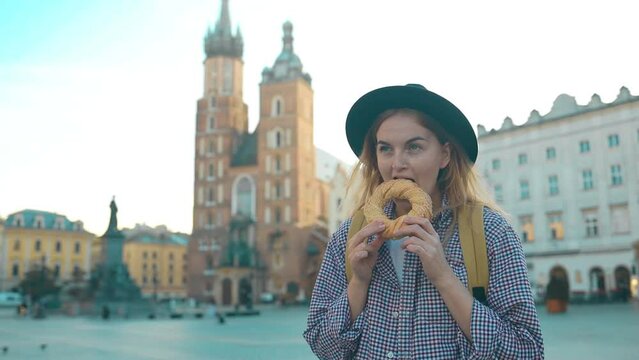 Young female tourist hand holding bagel, obwarzanek, pretzel. traditional Polish snack on Market Square in Cracow. 
