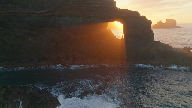 Great sunset at ocean coast, aerial view. Poris de Candelaria viewpoint, La Palma. Rays of setting sun break through hole in the rock off the coast of the Atlantic Ocean on La Palma island, Canary