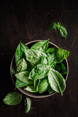 Bowl of basil leaves on wooden table. Top view.