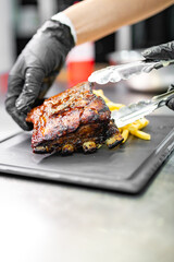 chef hand cooking Pork ribs with french fries and cheese sauce on kitchen