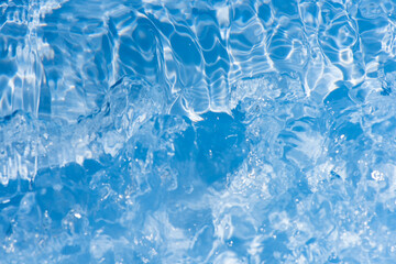 Defocus blurred transparent blue colored clear calm water surface texture with splashes reflection. Trendy abstract nature background. Water waves in sunlight with copy space. Blue watercolor shine.