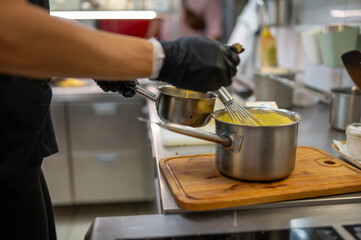 Chef hands cooking cheese sauce in the restaurant kitchen
