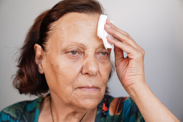 old woman complaining about summer heat. old woman wiping her sweat with a napkin