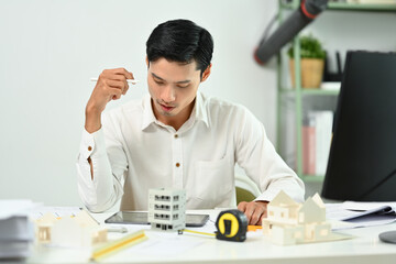 Focused engineer man using digital tablet, working on construction project of residential in office