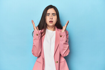 Young Caucasian woman on blue backdrop surprised and shocked.