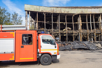 Fire location. Firefighter car. Ruins of burnt building. House was destroyed by fire. Fragment car for firefighters. Fire service vehicle. Truck for firefighters. Special equipment for firefighters