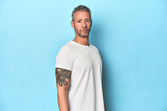 Middle-aged man posing on blue studio backdrop