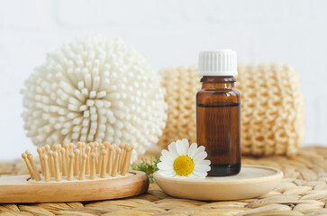 Small bottle with essential chamomile oil, wooden hairbrush and chamomile flower. Aromatherapy,...