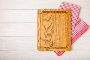 Wooden cutting board on a textured kitchen table. Wooden kitchen board and kitchen towel. Design.MOCKUP. Kitchenware. Place for text. Copy space. Recipe. Cooking concept.