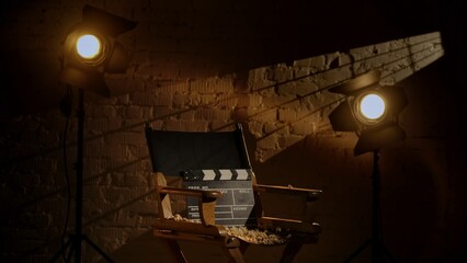 Closeup studio shot of clapperboard standing on director's chair, projectors at the background,...