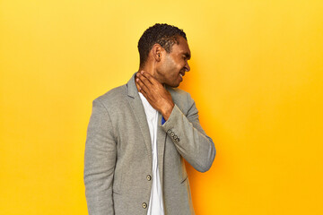 African American man in casual blazer, yellow studio, suffers pain in throat due a virus or...