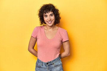 Curly-haired Caucasian woman in pink t-shirt happy, smiling and cheerful.