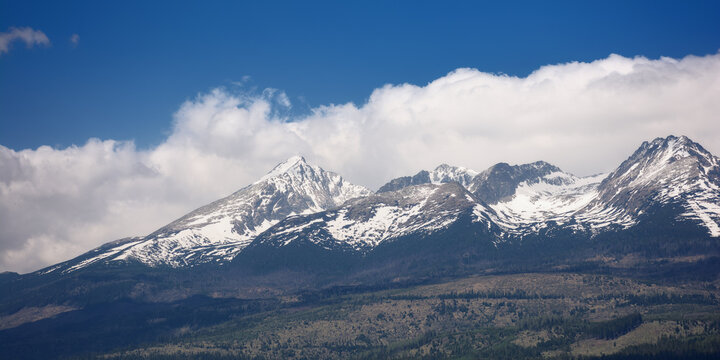 background image of high tatra peaks with snow in spring. sunny scenery with clouds on the blue sky
