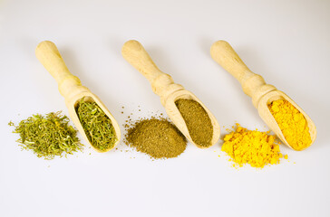 Turmeric, Hops-Sunels and other herbal spices in a wooden shovels and a handful of spices nearby