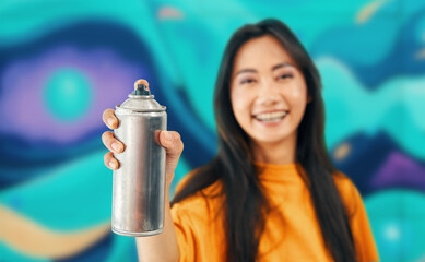 Smiling female street artist pointing spray paint can to camera