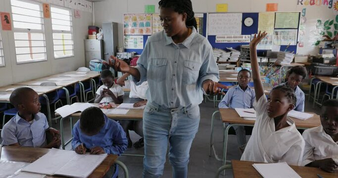 Close-up. Black African female teacher walking and teaching African children in a classroom in Africa