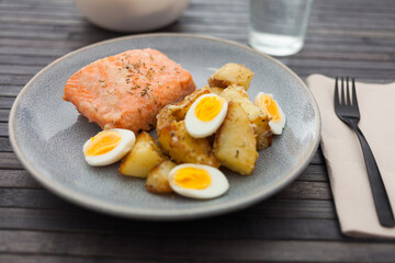 Baked salmon fillet with fried potato wedges and quail eggs halves