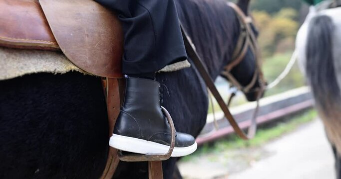 Child rider legs riding horse closeup 4k movie slow motion. Equestrian school concept