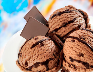 Chocolate ice cream balls with small pieces of chocolate and chocolate syrup.