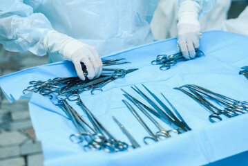 A nurse prepares medical instruments for surgery for surgeons