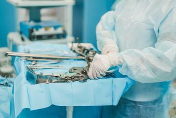 A nurse prepares medical instruments for surgery for surgeons