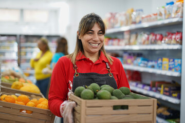 Happy latin woman working inside supermarket while holding avocado box - Healthy and fresh food market