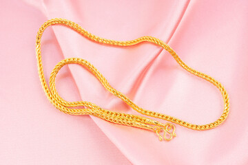 Gold Necklace on pink color silk background.