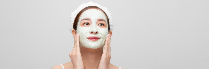 beautiful young woman doing cosmetic mask on her face - white background. Web banner