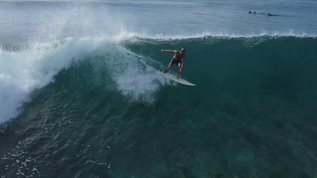 Aerial view of a surfer riding a blue wave taken at Maldives central atol. High quality 4k footage