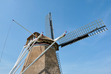 Closeup of the back of a traditional thatched dutch windmil in Hantum Friesland against a blue sky....