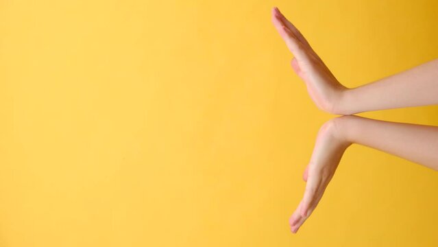 Vertical video of unknown young caucasian woman opening palms showing copy space, isolated over yellow color background wall in studio. Advertising area, mock-up for design. Presentation concept