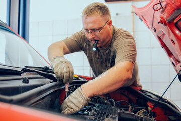 A Man with glasses Maintains a Car in a Garage