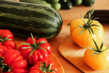 Fresh ripe big tomatoes, eggplant, veggies on a kitchen wooden workplace. Many raw vegetables background. Tomato, cucumbers. Cooker at home making a healthy veggie meal. Preparing vegetarian dish