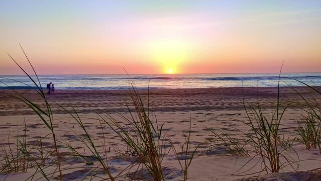 ein P&auml;rchen geht am Strand mit romantischem Sonnenuntergang spazieren, Mann, Frau, Meer, Abend, verliebt