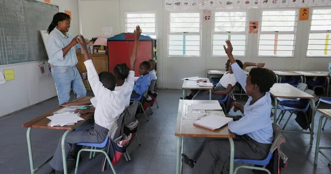 Close-up. Black African female teacher standing at the blackboard teaching children in a classroom in Africa