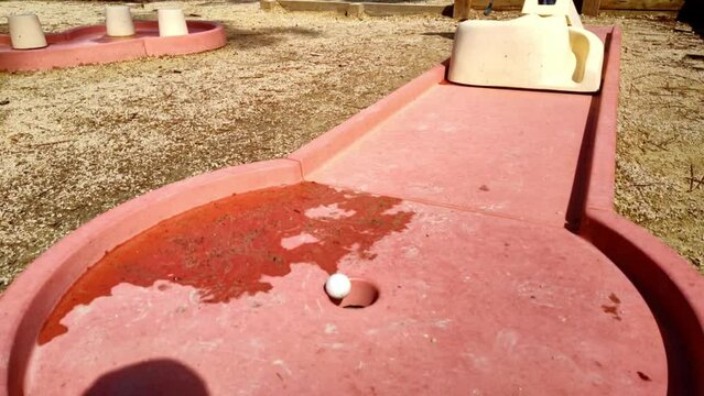 wei&szlig;er Minigolfball geht ins Loch, Treffer, Ziel, Loch, Ziel, Zeitlupe, Sieg, Erfolg