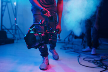 Close-up of cameraman using professional camera in shooting in studio