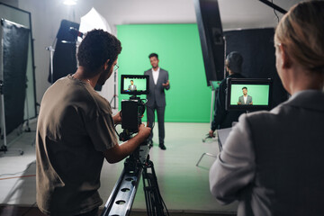 Operator using professional camera to shoot TV program with journalist in studio