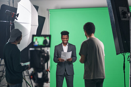 African American presenter in suit reading the script before shooting of TV program in studio