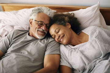 Happy senior biracial couple lying in bed and embracing at home