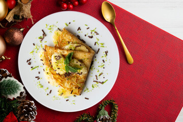 Crepe filled with pieces of banana marinated in lime juice on a table with Christmas decoration elements.