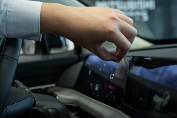 Naklejka premium A man removes the protective film from the dashboard of a new car. 