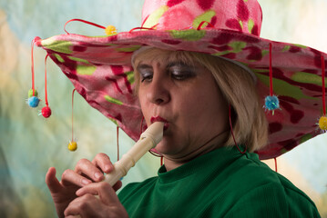 Clown in a hat. The buffoon grimaces and entertains. Portrait of a dressed up artist.